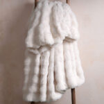 Cream white bubble bunny faux fur blanket draped on wooden ladder, soft neutral bedding