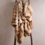 Tie-dye fawn bubble bunny faux fur blanket hanging on wooden ladder, trendy fluffy throw