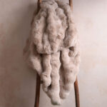 Tie-dye light brown bubble bunny faux fur blanket draped on wooden ladder, soft neutral throw