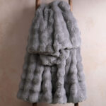 Light gray bubble bunny faux fur blanket draped on wooden ladder, cloud soft plush throw