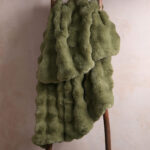 Sage green bubble bunny faux fur blanket hanging on wooden ladder, ultra fluffy plush bedding