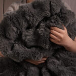 Person snuggling dark gray bubble bunny fluffy faux fur blanket, cozy warm throw