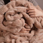 Person embracing fluffy light brown dual-sided elastic bunny faux fur blanket
