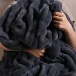 Cozy hug shot of tie-dye charcoal gray dual-sided elastic bunny faux fur blanket