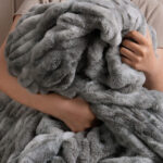 Person hugging ultra soft tie-dye gray dual-sided elastic bunny faux fur blanket