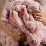 Person snuggling tie-dye pink dual-sided elastic bunny faux fur blanket