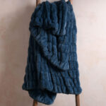 Deep blue dual-sided elastic bunny faux fur blanket hanging on wooden ladder, thick stretch cozy plush blanket