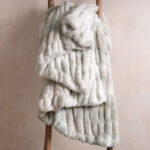 Tie-dye beige dual-sided elastic bunny faux fur blanket draped across wooden ladder, lightweight stretch throw