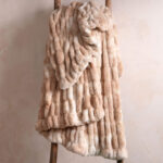 Tie-dye camel dual-sided elastic bunny faux fur blanket laid on wooden ladder, cloud soft stretch bedding