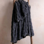 Tie-dye charcoal gray dual-sided elastic bunny faux fur blanket hanging on wooden ladder, cozy stretch plush blanket
